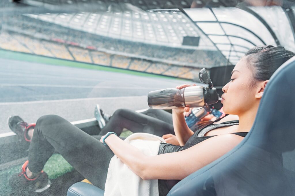 Woman hydrating after sports training at a stadium during a Formula 1 race break